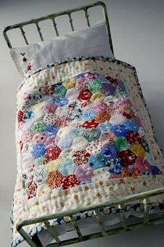 a small bed with a quilt on it's cover and pillow in the middle