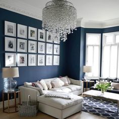 a living room with blue walls and pictures on the wall, chandelier hanging from the ceiling