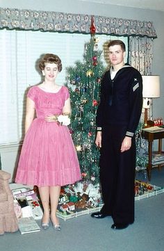 a man and woman standing in front of a christmas tree