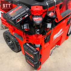 a red and black tool box with tools on it's back end in a garage