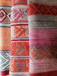 several different colored knitted blankets hanging up