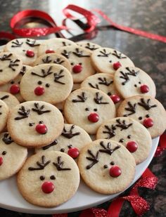 a plate full of cookies with reindeer faces on them and red bows around the edges