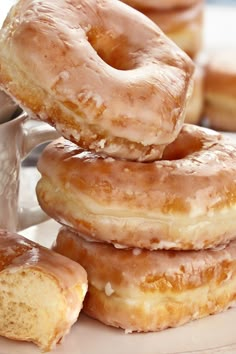 several glazed donuts stacked on top of each other next to a cup of coffee