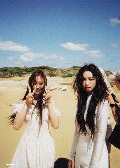 two women in white dresses standing on the beach