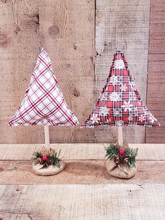 two small christmas trees sitting on top of a wooden table next to eachother