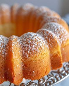 a bundt cake with powdered sugar on top sits on a silver platter