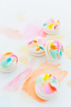 three colorful macaroons sitting on top of a white table covered in icing