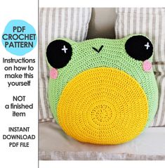 a crocheted frog pillow sitting on top of a bed