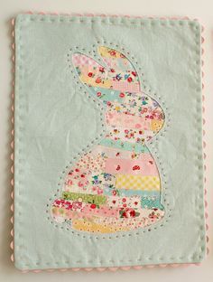 a close up of a piece of fabric on a wall with a bunny patchwork design