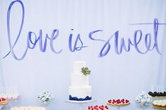 a table topped with cakes and cupcakes next to a sign that says love is sweet