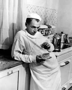 black and white photograph of a man in the kitchen holding a plate with food on it