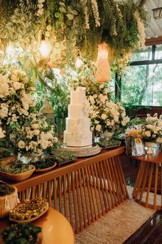 a wedding cake sitting on top of a wooden bench next to flowers and greenery