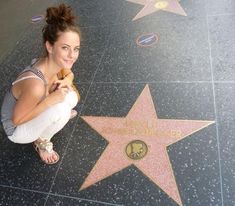 a woman sitting on the hollywood walk of fame holding a donut in her right hand