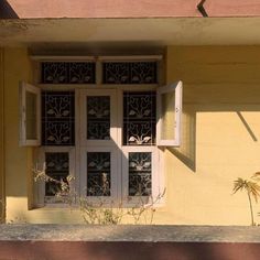 an open window on the side of a yellow building