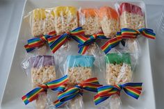 rainbow lollipops are wrapped in plastic and tied with colorful ribbons on a white tray