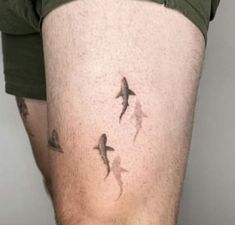 a man with tattoos on his thigh and some sharks