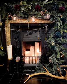 a fireplace decorated with candles and greenery next to a deer antelope ornament