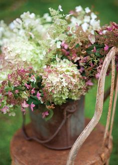 a bucket filled with lots of flowers on top of a wooden table next to a ribbon