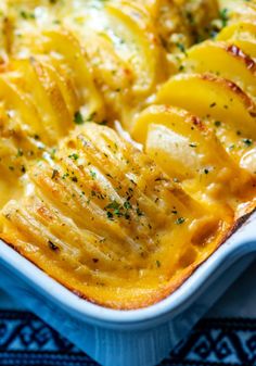 a casserole dish with potatoes and cheese in it on a blue place mat