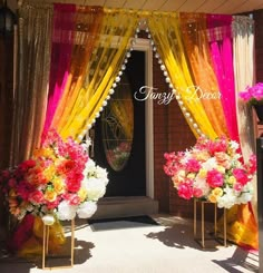 two vases with flowers are sitting in front of a door decorated with yellow and pink drapes