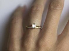 a woman's hand with a diamond ring on top of her finger, close up