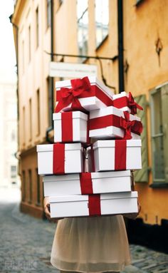 a woman carrying stacks of white and red gift boxes