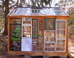 a small building with lots of windows in the front and side doors on top of it