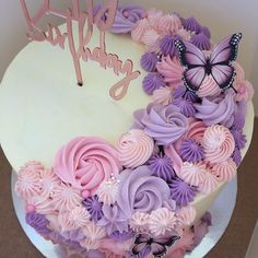 a birthday cake with pink and purple frosting flowers on the bottom, and a butterfly topper