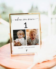 a wooden table topped with a sign that says, when we were 1 and has two pictures on it