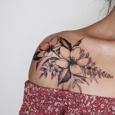 a woman's shoulder with flowers and leaves tattooed on the back of her shoulder