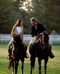 two people riding on the backs of brown horses