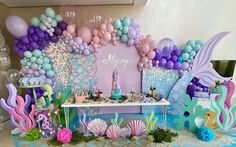 an under the sea themed birthday party with balloons, decorations and mermaid tail cake toppers