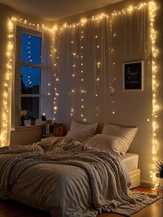 an unmade bed with lights hanging from the ceiling and curtains on the wall above it