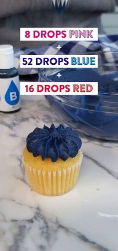 a blue cupcake sitting on top of a marble counter next to a bottle of water