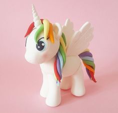 a toy pony with multicolored manes standing on a pink surface