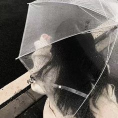 a woman holding an umbrella while standing on the side of a road in the rain