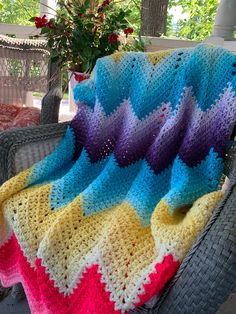 a crocheted blanket sitting on top of a wicker chair