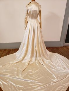 the back of a wedding dress on display in a room with wooden floors and white walls