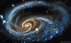 two spiral galaxy like objects in the sky with stars around them, and one is blue