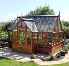 a small wooden greenhouse in the middle of a garden