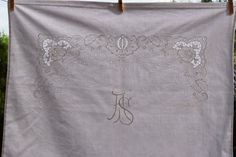 an embroidered monogrammed cloth hanging on a clothesline with the letter j in it