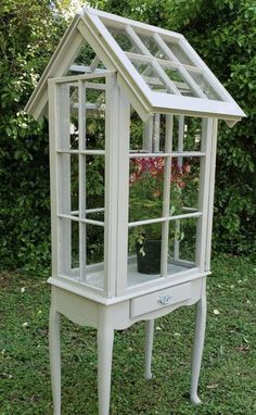 a small white house shaped planter with flowers inside