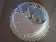 a frosted cake decorated with snowflakes and trees