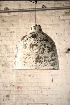 an old light hanging from a brick wall in a room with exposed lighting and white bricks