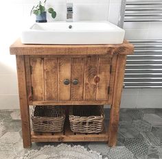 a wooden sink cabinet with two baskets underneath it and a towel rack on the side