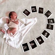 a baby laying on top of a white blanket next to many black and white photos