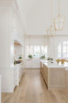 a large kitchen with white cabinets and wood flooring on the walls, along with an island in the middle