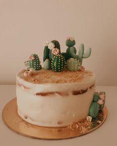 a cake decorated with cacti and frosting on a gold plated platter