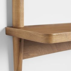 a close up of a wooden shelf against a white wall