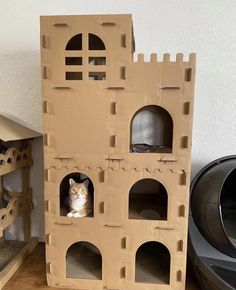 a cardboard castle with a cat sitting in it